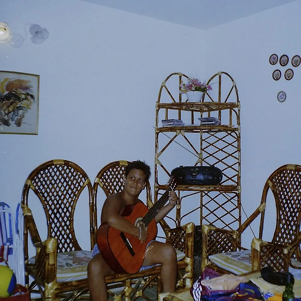 Guille adolescente tocando la guitarra criolla en el living de casa